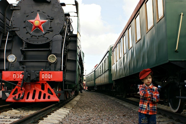 un petit garçon à côté de deux trains